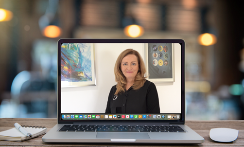 Laptop on a wooden desk with a lady in center